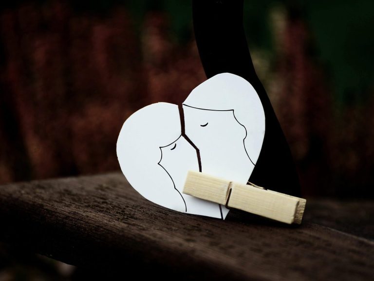 Paar Zwei umarmende Köpfe in Form eines Herzens, gehalten von einer Wäscheklammer.